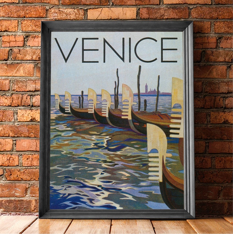 May include: Framed art print featuring the word "VENICE" above a depiction of gondolas on the water. The artwork showcases a row of gondolas with their distinctive yellow and white accents, reflecting in the rippling water. A cityscape is visible in the distance.