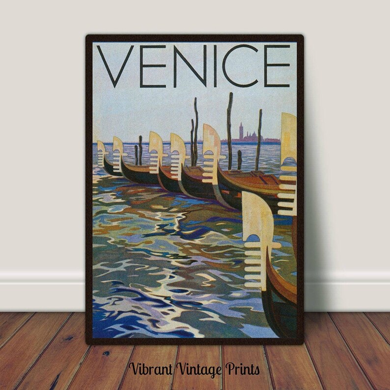 May include: Vintage Venice travel poster print. The artwork features a row of gondolas on the water with the city skyline in the background. The word "VENICE" is printed at the top. The print is framed in a dark brown frame.