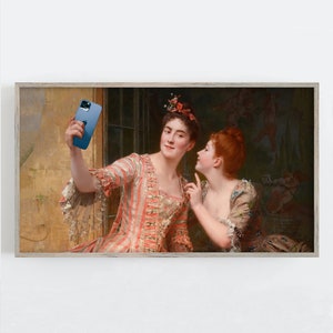 Könnte beinhalten: Gerahmter Kunstdruck eines klassischen Gemäldes mit zwei Frauen. Eine Frau hält ein blaues Smartphone und macht ein Selfie. Die andere Frau schaut auf das Telefon und zeigt darauf. Die Frauen tragen historische Kleidung.