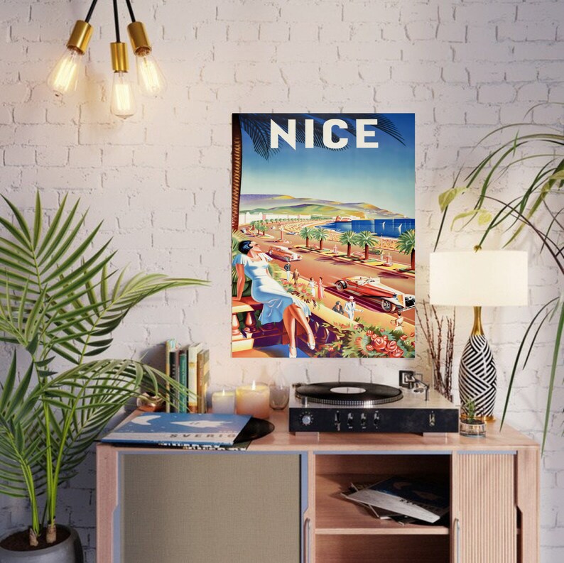 Puede incluir: Un cartel de viaje vintage para Niza, Francia, que presenta a una mujer con un vestido azul claro, palmeras y coches cl&aacute;sicos. La palabra "NICE" se muestra en letras blancas grandes sobre un fondo de cielo azul. El cartel evoca una sensaci&oacute;n de viaje y ocio.