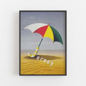 May include: Framed print of a beach scene with a colourful umbrella. The umbrella has white, red, yellow, and green panels. The word "Jersey" is printed in white on the sand. The image is framed in black.