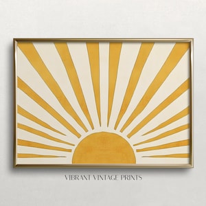 May include: A framed print of a stylized sun with yellow rays on a cream background. The sun is a solid yellow color and the rays are thin and pointed. The frame is a simple gold color.