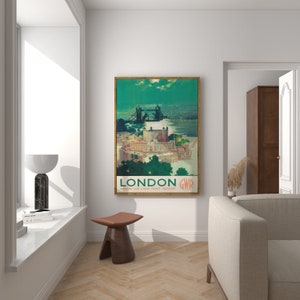 May include: A vintage travel poster featuring a scenic view of the Tower Bridge in London, England. The poster is in a wooden frame and has a green background with the text "LONDON GWR ENQUIRE FOR CHEAP TICKET FACILITIES".