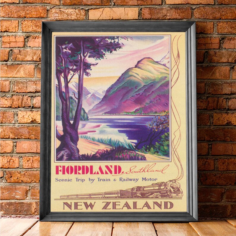 Puede incluir: P&oacute;ster de viaje vintage enmarcado para Fiordland, Southland, Nueva Zelanda. La obra de arte presenta un paisaje esc&eacute;nico con un lago, monta&ntilde;as y un tren. El p&oacute;ster tiene un fondo color crema con el texto "Scenic Trip by Train & Railway Motor."