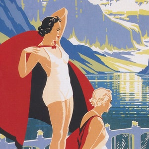 May include: Two women in vintage swimwear stand in front of a mountain lake. One woman wears a white swimsuit and a red cape. The other woman wears a white swimsuit and a red and black cape. The lake is blue and the mountains are green and white.