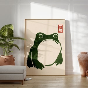 May include: A minimalist art print featuring a green frog silhouette on a beige background. The print has a red seal with the Japanese character "開" (kai) meaning "open" in the upper right corner.