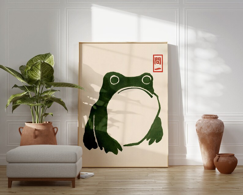 May include: A minimalist art print featuring a green frog silhouette on a beige background. The print has a red seal with the Japanese character "開" (kai) meaning "open" in the upper right corner.