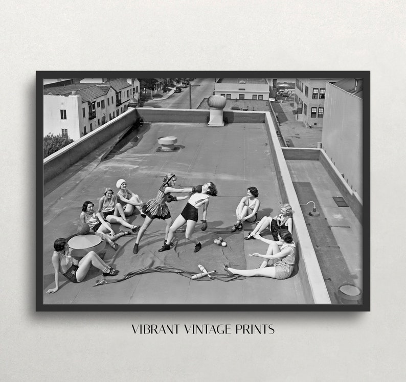 Puede incluir: Impresi&oacute;n vintage en blanco y negro enmarcada que muestra a mujeres en una azotea, algunas boxeando, otras relaj&aacute;ndose. La impresi&oacute;n incluye el texto "VIBRANT VINTAGE PRINTS" en la parte inferior. Se ven edificios al fondo.