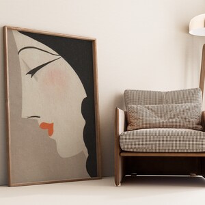 May include: A framed art print featuring a side profile of a woman's face with closed eyes, red lips, and black hair. A wooden armchair with a checkered pattern cushion and pillow sits beside the artwork. A wooden floor lamp with a chrome shade is also in the image.