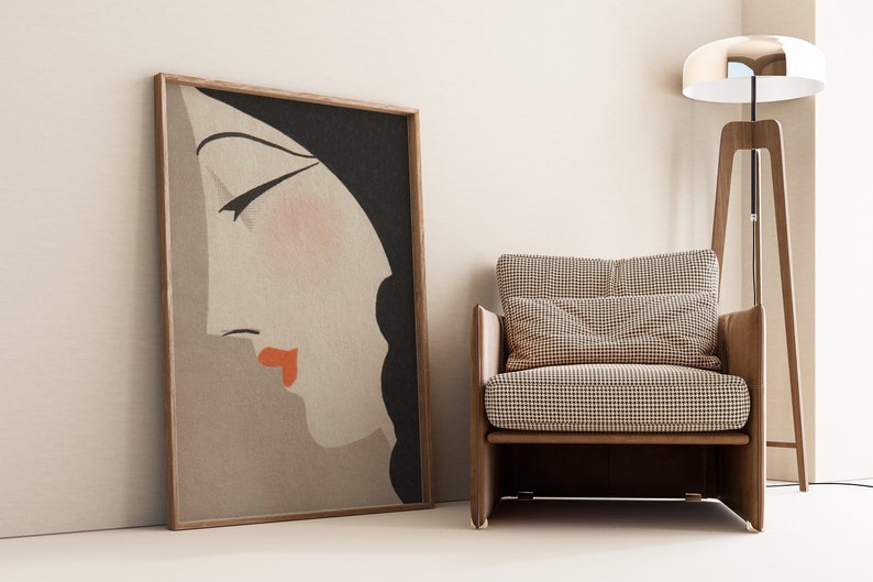 May include: A framed art print featuring a side profile of a woman's face with closed eyes, red lips, and black hair. A wooden armchair with a checkered pattern cushion and pillow sits beside the artwork. A wooden floor lamp with a chrome shade is also in the image.