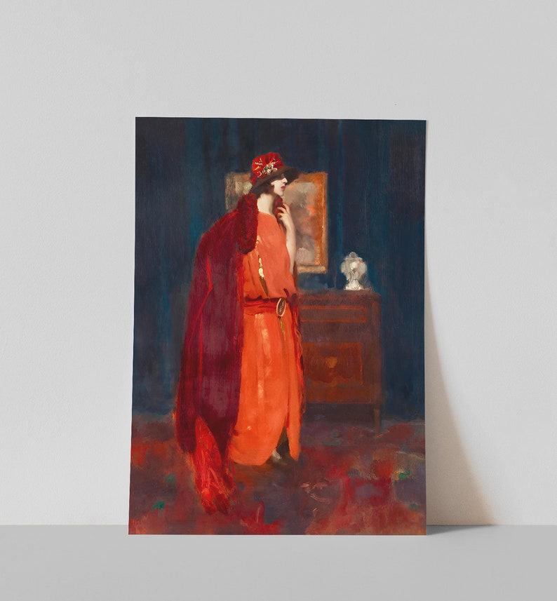 May include: A woman in a red dress and a red hat stands in a room with a dark blue wall. She is wearing a long, flowing red cloak and has a thoughtful expression on her face. The room is decorated with a dark wooden dresser and a framed picture.