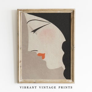 May include: A framed vintage art print featuring a stylized profile of a woman. The artwork has a muted color palette with a peach complexion, red lips, and black hair. The print is in a gold-colored frame, and the text "VIBRANT VINTAGE PRINTS" is at the bottom.