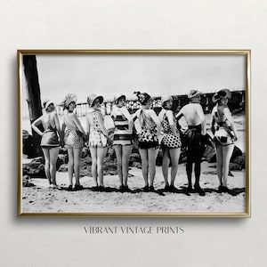 Könnte beinhalten: Schwarz-Weiß-Vintage-Fotografie einer Gruppe von Personen in Badeanzügen und Hüten am Strand. Das Bild ist in einem goldfarbenen Rahmen gerahmt. Der Text "VIBRANT VINTAGE PRINTS" befindet sich am unteren Rand des Bildes.