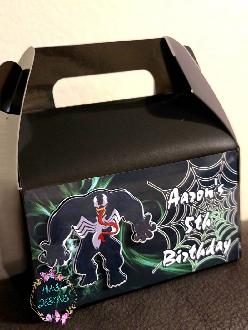 May include: A black and green favor box with a Venom character graphic and the text "Aaaron's 5th Birthday" on the front.
