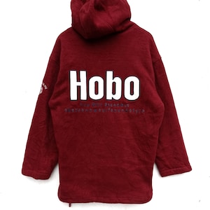 May include: A maroon fleece hoodie with a white "Hobo" logo and the text "You Will Survive" in smaller white letters below. The text "skate snow surf sound style" is printed in blue below the logo.
