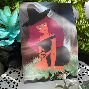 May include: A digital illustration of a woman with long, red hair wearing a black witch hat and a black dress. She has a crescent moon tattoo on her arm and a heart tattoo on her chest. She is sitting in a field of green grass with yellow flowers.
