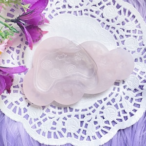 May include: A light pink silicone mold shaped like a cloud with a raised design of a video game controller inside.