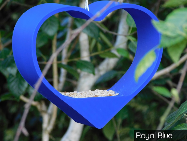 May include: A royal blue heart-shaped bird feeder with birdseed inside.