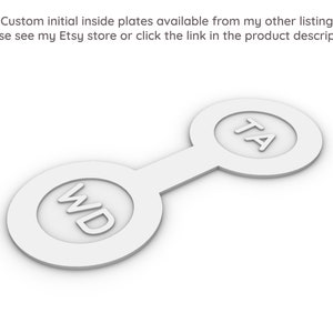 May include: Two white, round, connected plates with the initials "WD" and "TA" printed on them.