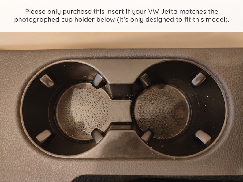 May include: Close-up of a black plastic cup holder with two empty cup slots. The cup holder has a textured surface and is designed to fit a specific car model.