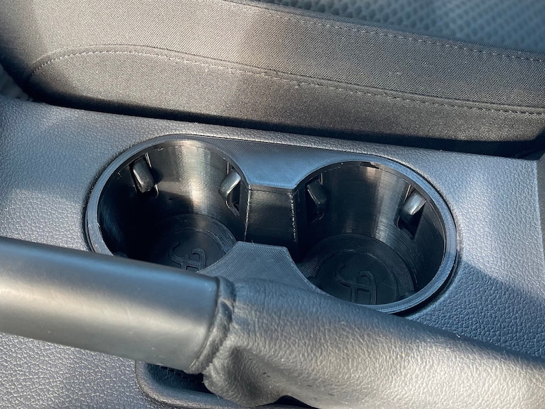 May include: Close-up of a black car cup holder with two empty cup slots.