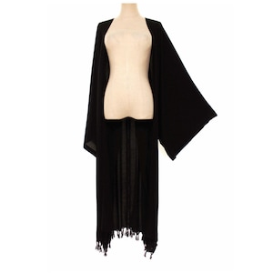 May include: A long, black kimono-style cardigan with wide sleeves and a fringed hem. The open-front design drapes over a mannequin, showcasing the garment's flowing silhouette and lightweight fabric.