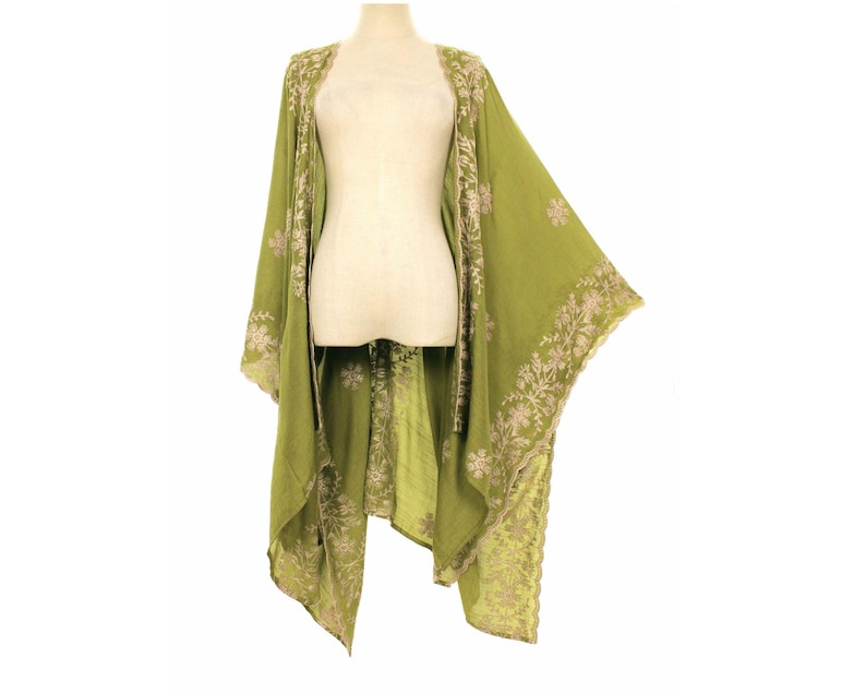 May include: A flowing, olive green kimono-style garment with intricate floral embroidery in a lighter shade. The open-front design drapes elegantly, showcasing the detailed patterns along the edges and sleeves. The garment is displayed on a mannequin.