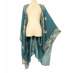 May include: Teal-colored embroidered kimono-style wrap. The wrap features intricate floral embroidery in a contrasting light beige thread along the edges and around the shoulders. The garment is displayed on a mannequin.