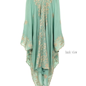 May include: A flowing, mint green garment with intricate gold embroidery. The back view reveals a detailed floral pattern along the seams and edges. The sleeves are wide and the fabric drapes elegantly. The text "back view" is visible.