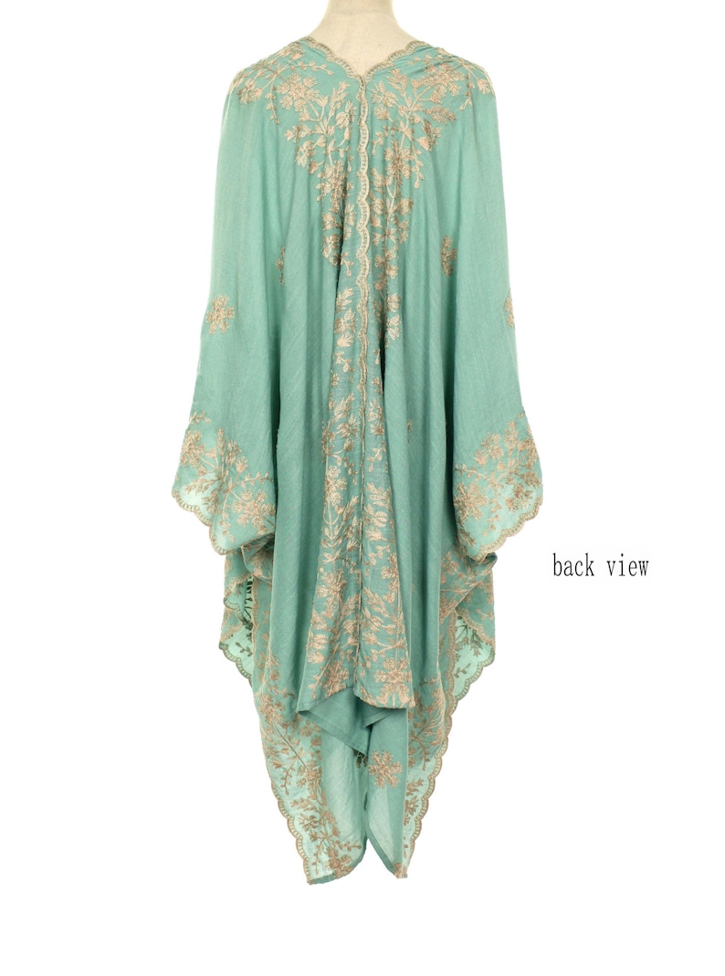 May include: A flowing, mint green garment with intricate gold embroidery. The back view reveals a detailed floral pattern along the seams and edges. The sleeves are wide and the fabric drapes elegantly. The text "back view" is visible.