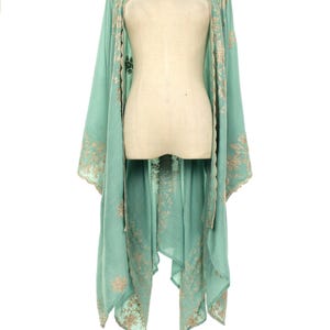 May include: A flowing, mint green kimono-style garment with intricate gold embroidery along the edges and sleeves. The lightweight fabric drapes elegantly, creating a relaxed silhouette. The embroidery features floral and geometric patterns.