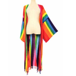 May include: A long, open-front kimono featuring a vibrant, multi-colored rainbow stripe pattern in shades of red, orange, yellow, green, blue, and purple. The garment has wide, loose sleeves and a straight hemline finished with decorative fringe.