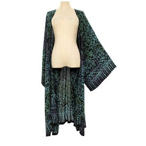 May include: A long, open-front kimono robe featuring a dark black base with an intricate, repeating pattern in shades of teal, turquoise, and purple. The garment has wide, flowing sleeves and a straight hemline that falls below the knees.