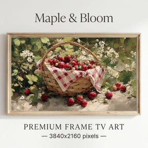 May include: A framed print titled "Maple & Bloom" featuring a still life of a woven basket filled with ripe red strawberries. The basket has a red and white checkered cloth. The background shows green foliage and white flowers.