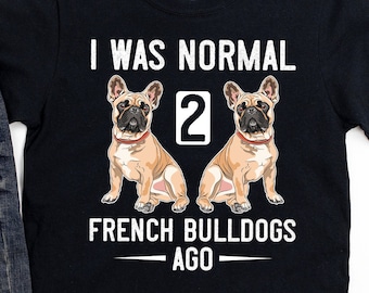 May include: Black t-shirt with white text that reads "I was normal 2 French Bulldogs ago". The shirt features a cartoon image of two French Bulldogs.