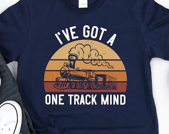 May include: A navy blue t-shirt with a vintage-style illustration of a train engine and the text "I've got a one track mind".