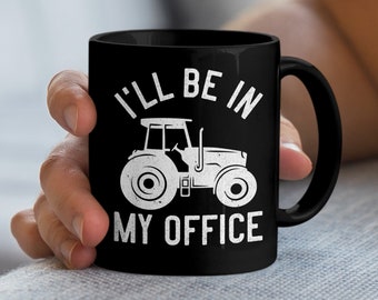 Könnte beinhalten: Schwarze Kaffeetasse mit einem weißen Traktor-Motiv und dem Text "I'll be in my office".