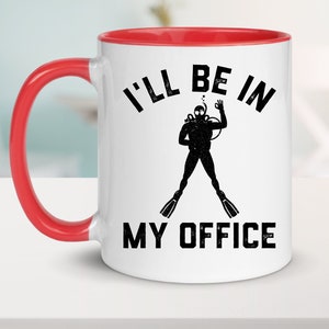 Puede incluir: Taza de cer&aacute;mica blanca con interior y asa rojos. La taza presenta el texto negro "I'LL BE IN MY OFFICE", junto con una silueta negra de un buzo haciendo el gesto de la mano "ok". La taza est&aacute; sobre una superficie blanca.