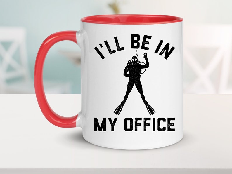 Puede incluir: Taza de cer&aacute;mica blanca con interior y asa rojos. La taza presenta el texto negro "I'LL BE IN MY OFFICE", junto con una silueta negra de un buzo haciendo el gesto de la mano "ok". La taza est&aacute; sobre una superficie blanca.