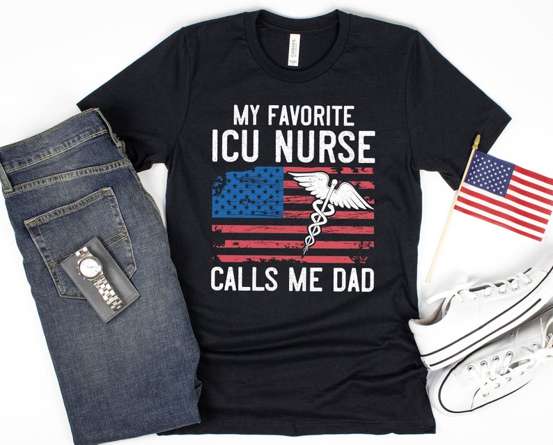May include: Black t-shirt with a distressed American flag design and the text "My Favorite ICU Nurse Calls Me Dad".