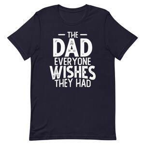 May include: Navy blue t-shirt with white text that reads "The Dad Everyone Wishes They Had".