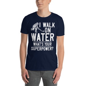 May include: A navy blue t-shirt with a white graphic of a hockey player skating on water. The text "I walk on water" and "What's your superpower?" is printed in white.