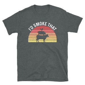 May include: A dark heather grey t-shirt with a vintage-style sunset graphic and the text "I'd Smoke That". The graphic features a chicken, pig, and cow stacked on top of each other.
