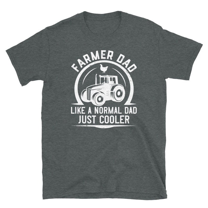 May include: A dark gray t-shirt with a white graphic design. The graphic features a tractor with a chicken on top and the text "Farmer Dad Like a Normal Dad Just Cooler".