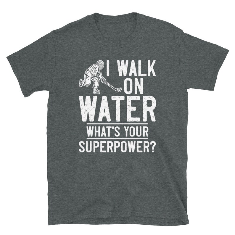 May include: A dark heather grey t-shirt with a white graphic of a hockey player skating on water. The text "I walk on water" is above the graphic and "What's your superpower?" is below the graphic.