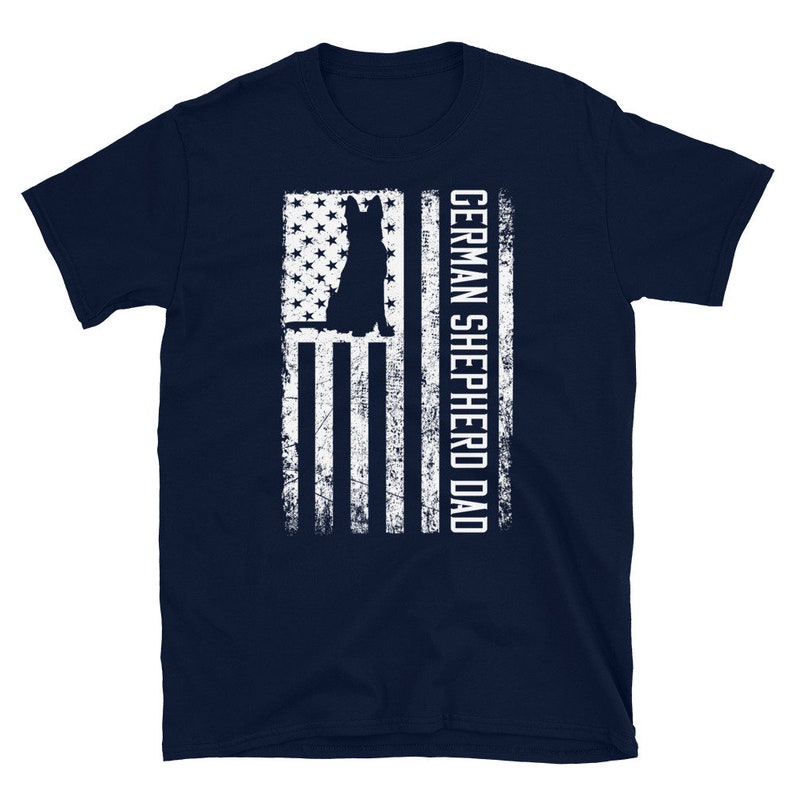 May include: Navy blue t-shirt with a white silhouette of a German Shepherd dog in front of an American flag. The text "GERMAN SHEPHERD DAD" is printed on the right side of the flag.