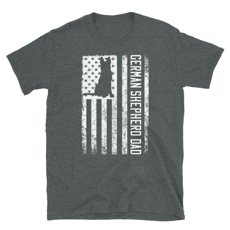 May include: A dark heather grey t-shirt with a white silhouette of a German Shepherd dog in front of an American flag. The text "GERMAN SHEPHERD DAD" is printed on the right side of the flag.
