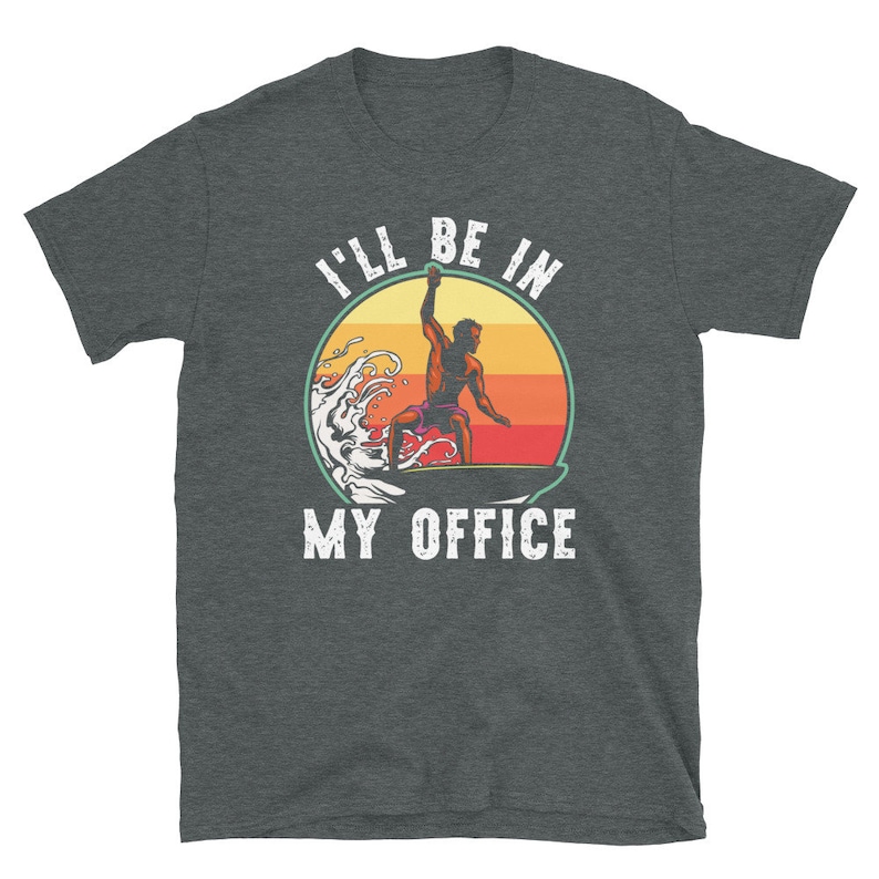 May include: A dark grey t-shirt with a retro-style illustration of a surfer riding a wave. The text "I'll be in my office" is printed on the shirt.