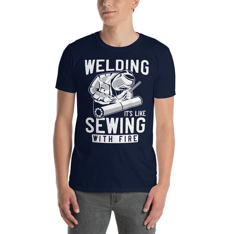 May include: A navy blue t-shirt with a white graphic of a welder and the text "Welding It's Like Sewing With Fire".
