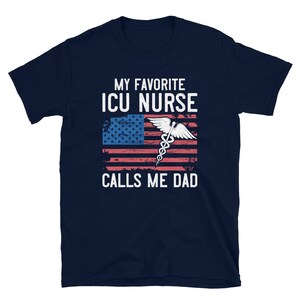 May include: Navy blue t-shirt with a white and red American flag design and the text "My Favorite ICU Nurse Calls Me Dad".